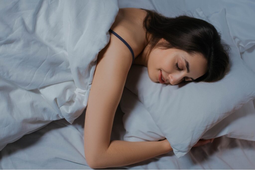Person sleeping deeply in bed representing the delta brain wave state of deep sleep and recovery