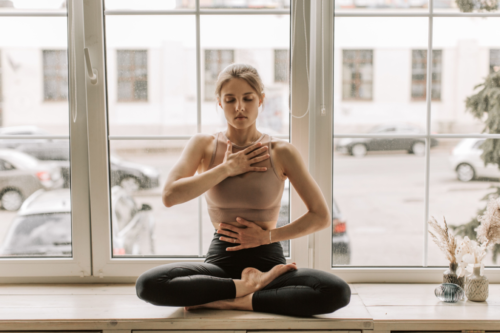 Woman visualizing love during meditation with hands placed on her body.