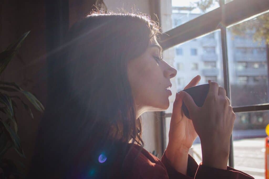 Woman in quiet morning moment with tea before starting her day representing the daily tarot check-in routine