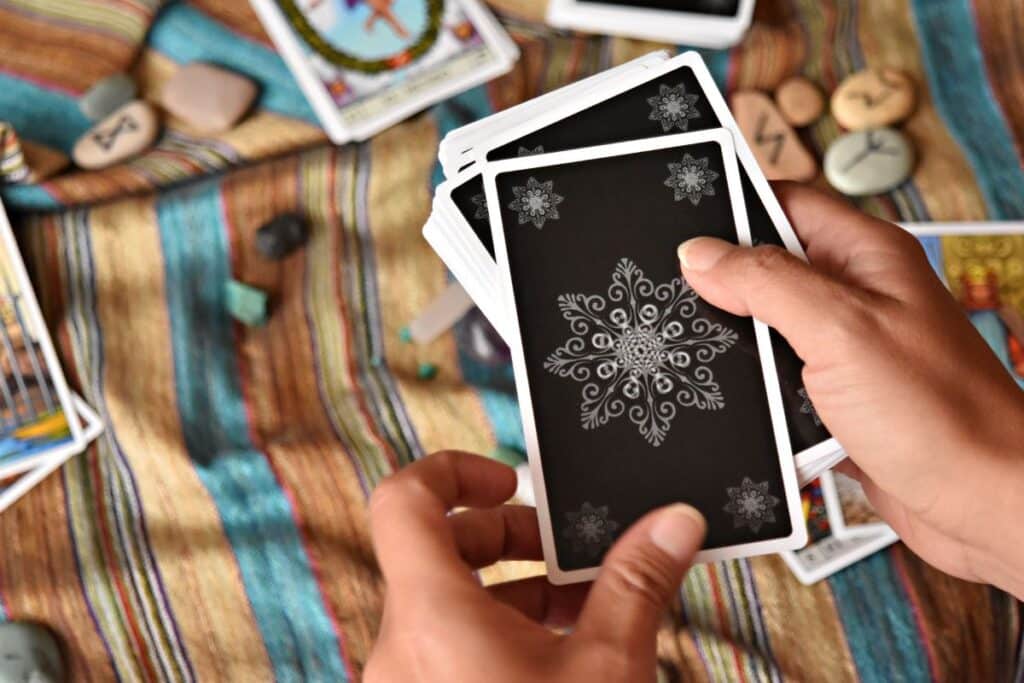 Hands shuffling a tarot card deck before laying out a three card spread